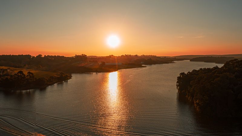 Lancha cruza o lago ao pôr do sol