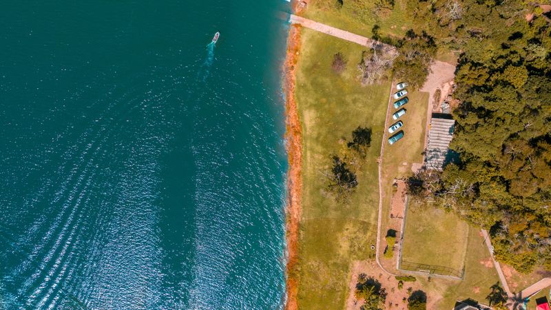 Vista de cima da margem de um lago com um barco